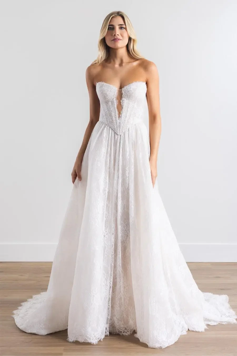 Model is wearing an a-line sleeveless bridal gown that has 3d florals peeking out of the bodice 