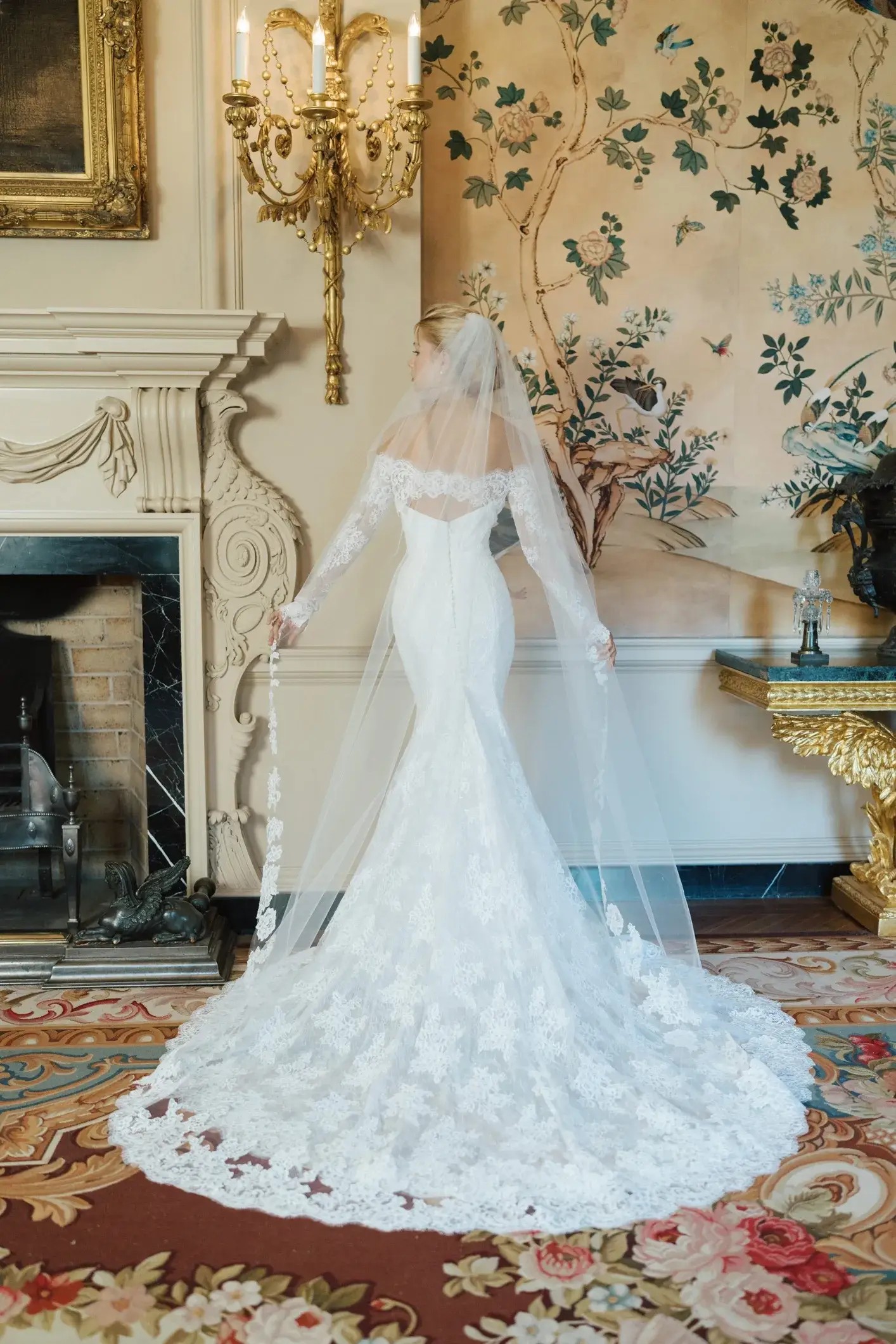 Model is wearing a strapless gown with a scalloped hem and lace underlay