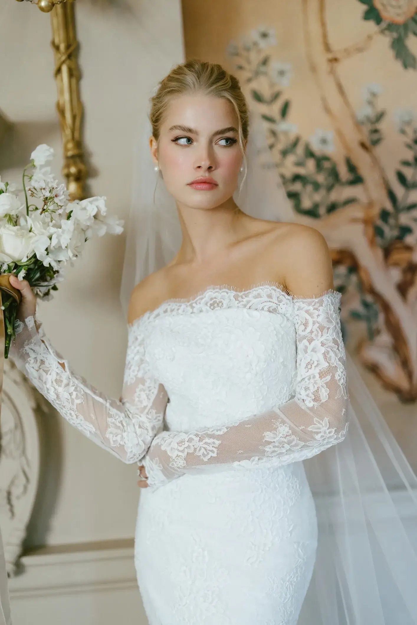 Model is wearing a strapless gown with a scalloped hem and lace underlay