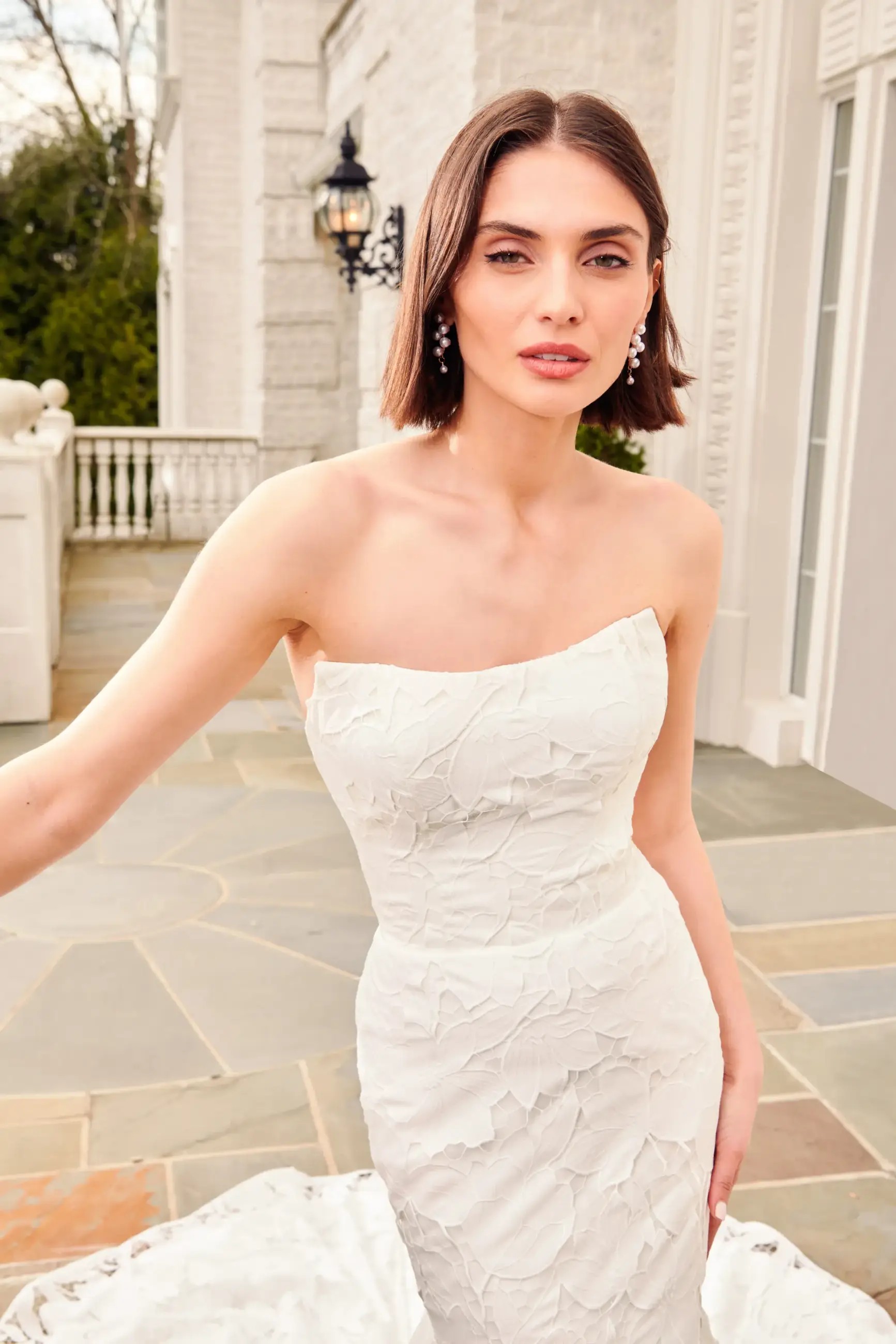 Model is wearing a fit and flare wedding dress with a strapless bodice and laser cut floral detailing