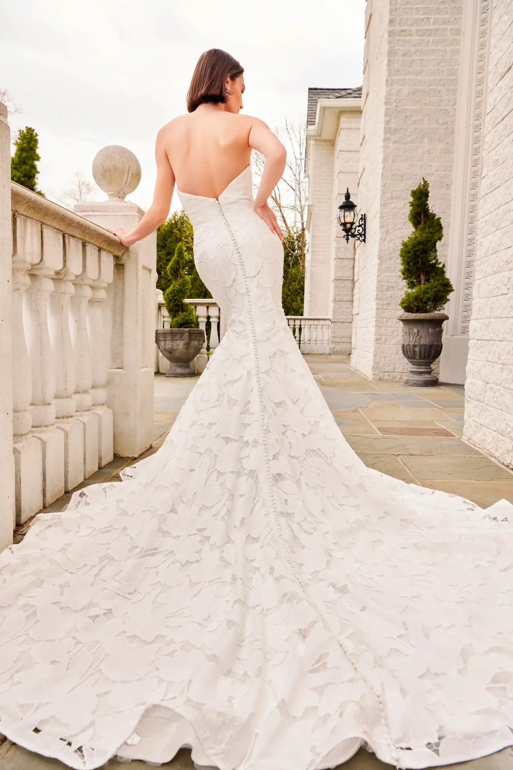 Model is wearing a fit and flare wedding dress with a strapless bodice and laser cut floral detailing