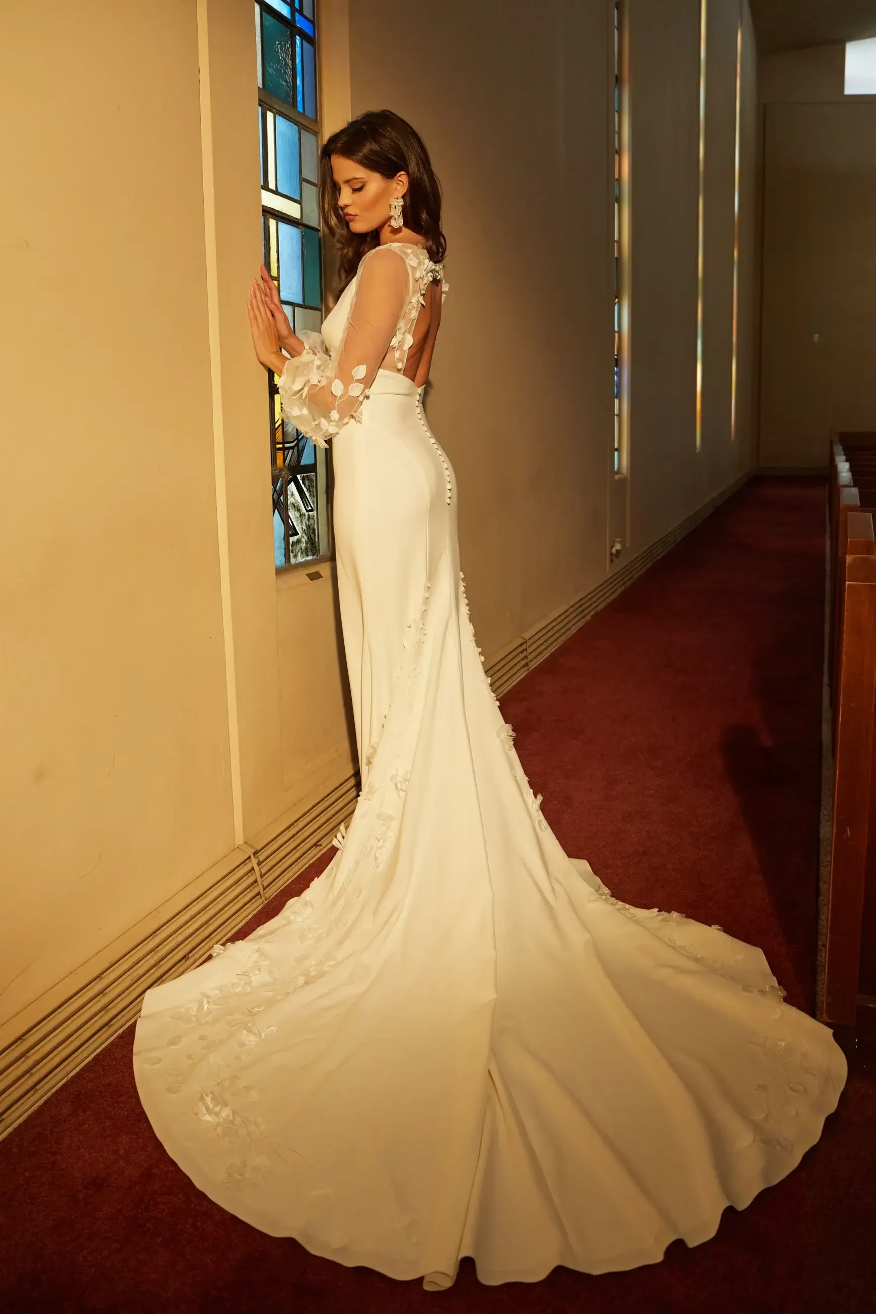 model is wearing a sleeveless fit and flare bridal gown with a long train