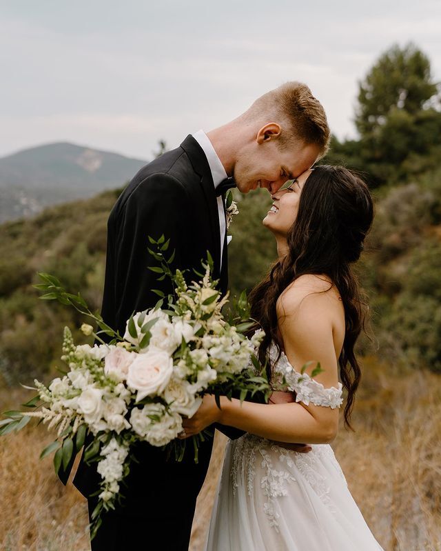 Сouple wearing a white gown and a black suit with a flowers