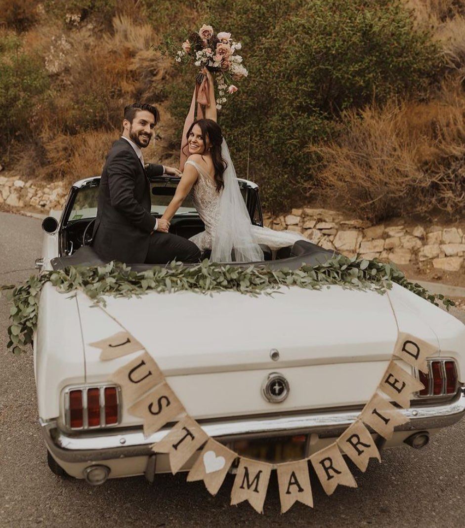 Сouple wearing a white gown and a black suit in a car