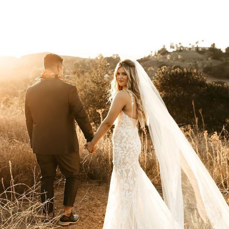 Сouple wearing a white gown and a black suit om the grass