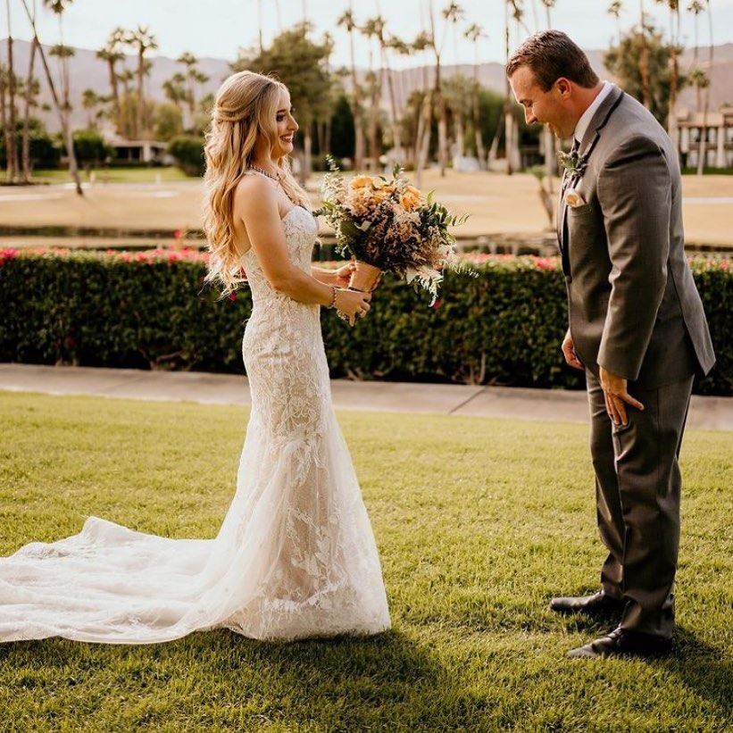 Сouple wearing a white gown and a dark-gray suit on the grass