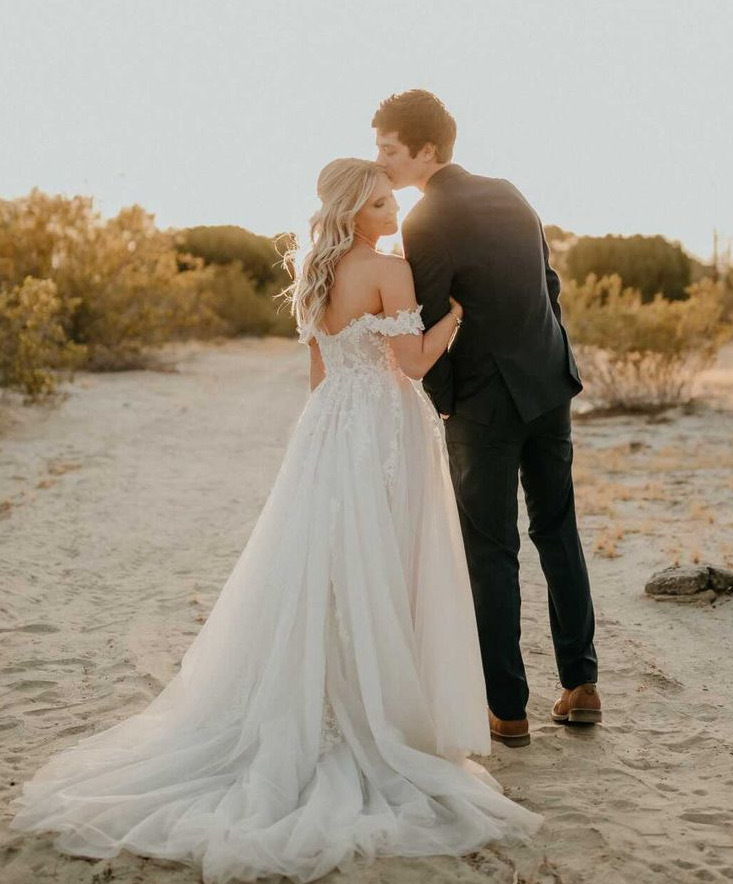 Сouple wearing a white gown and a black suit on the beach